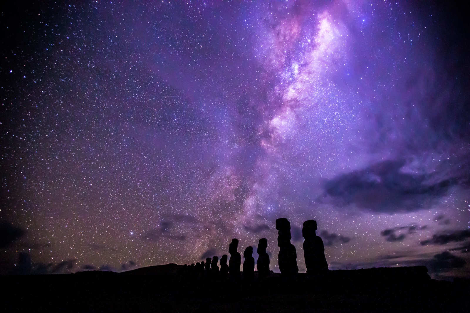 The moai of Ahu Tongariki silhouetted against a violet Milky Way on Easter Island