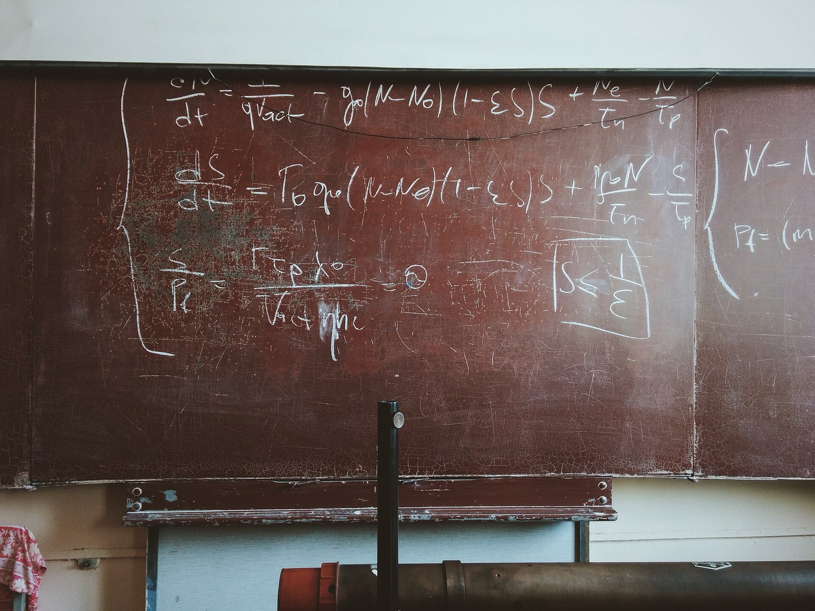 Chalk differential equations across a worn red-brown blackboard