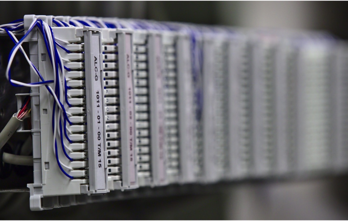 A long labelled patch panel receding into shallow focus, blue-and-white pairs punched down