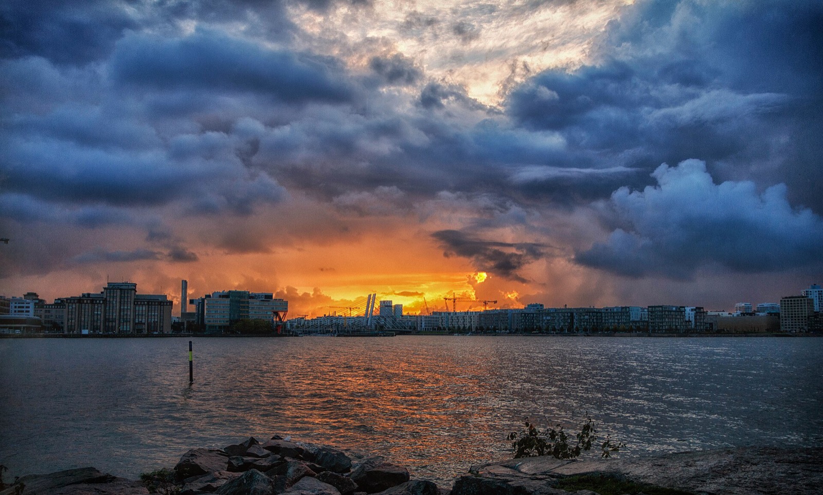 Storm clouds breaking over the Helsinki waterfront, orange light along the horizon