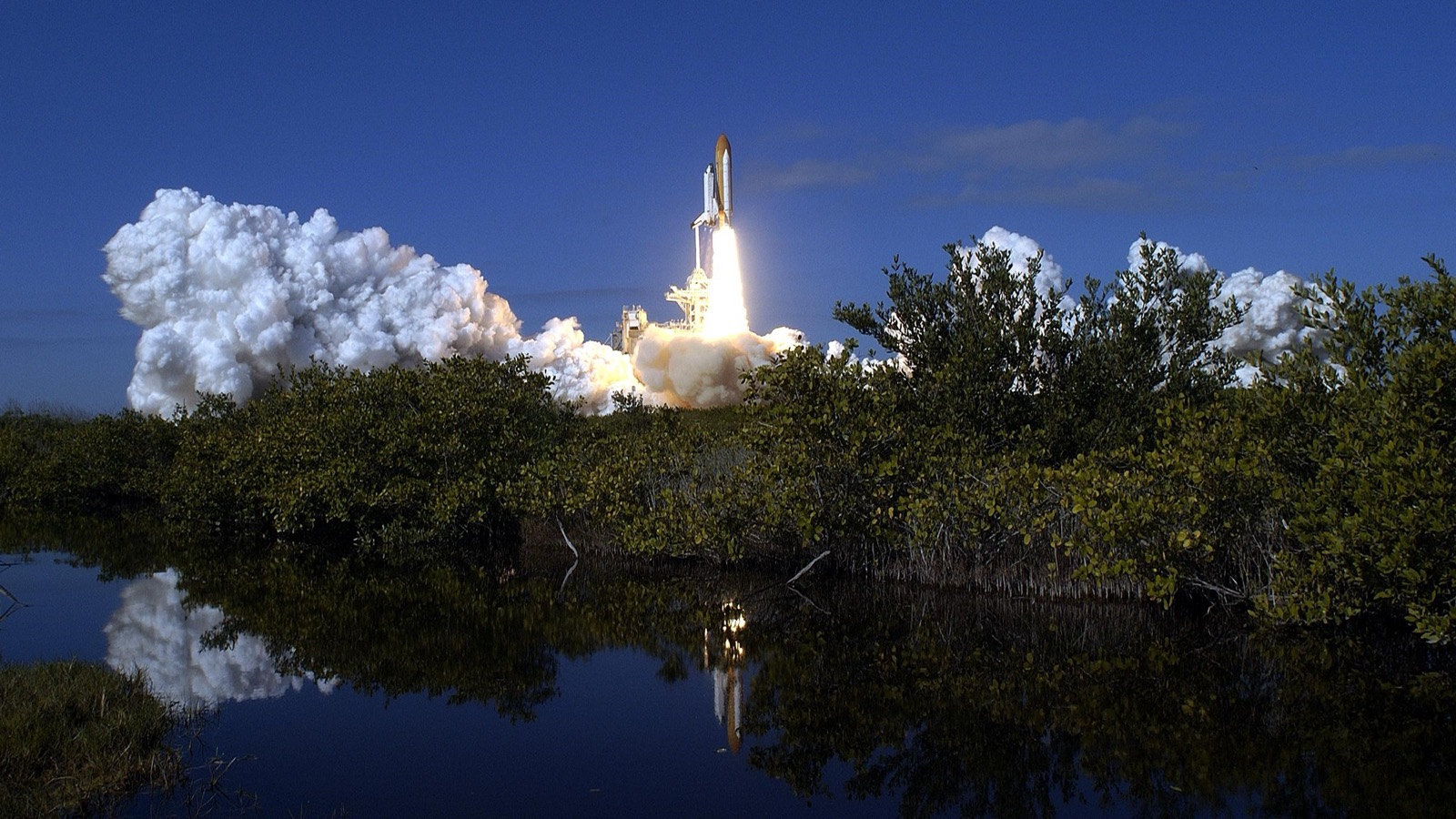 Space Shuttle Columbia launches on STS-107 from Pad 39A, its plume reflected in the marsh water at Kennedy Space Center, January 16, 2003