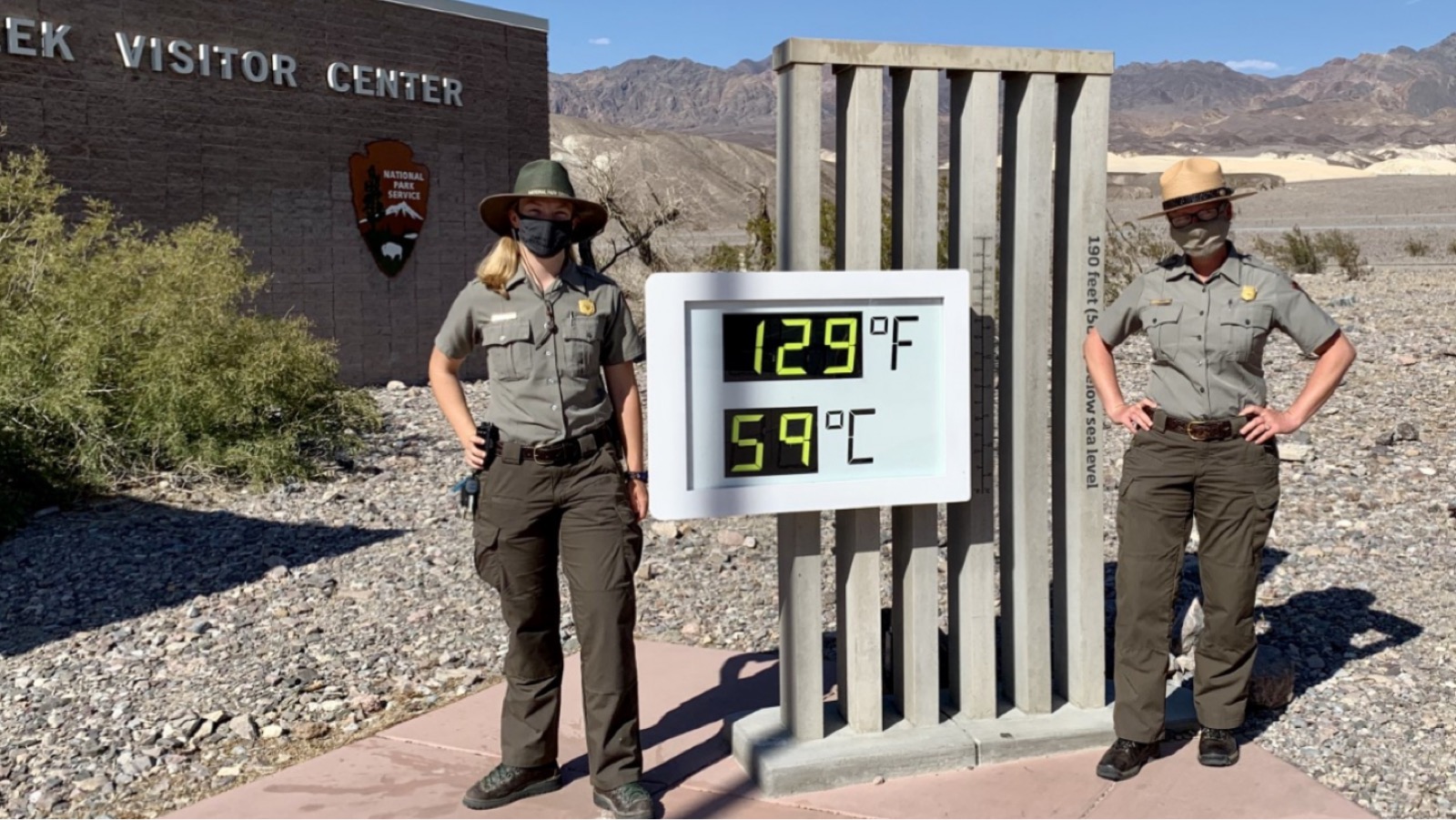 A digital sign displays a scorching temperature reading against a bleached desert sky.