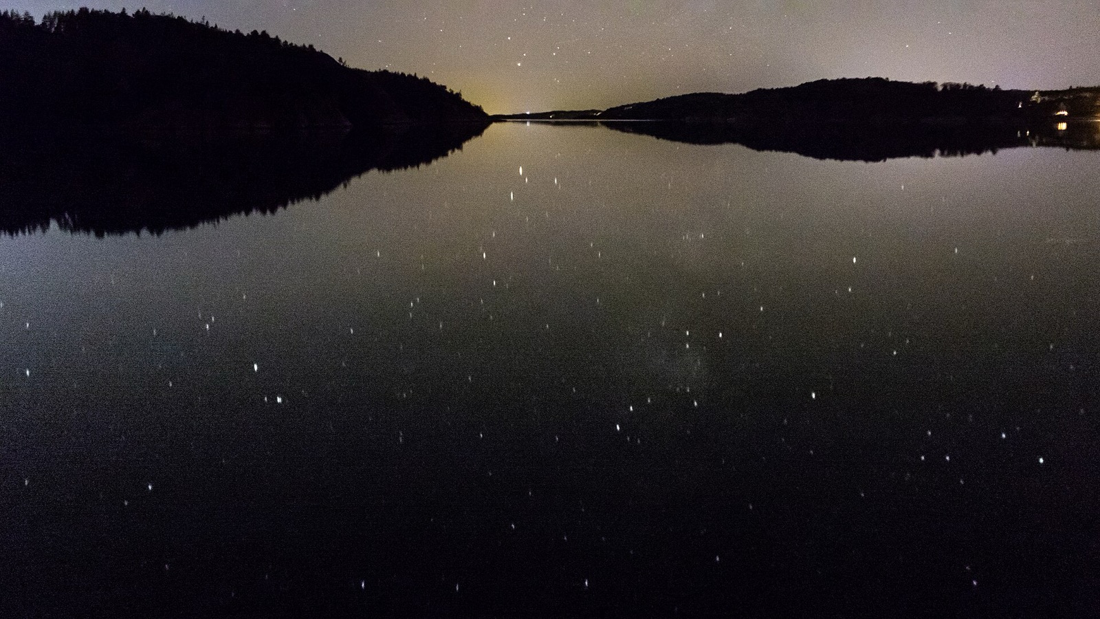 The Milky Way arcs over a dark night landscape.