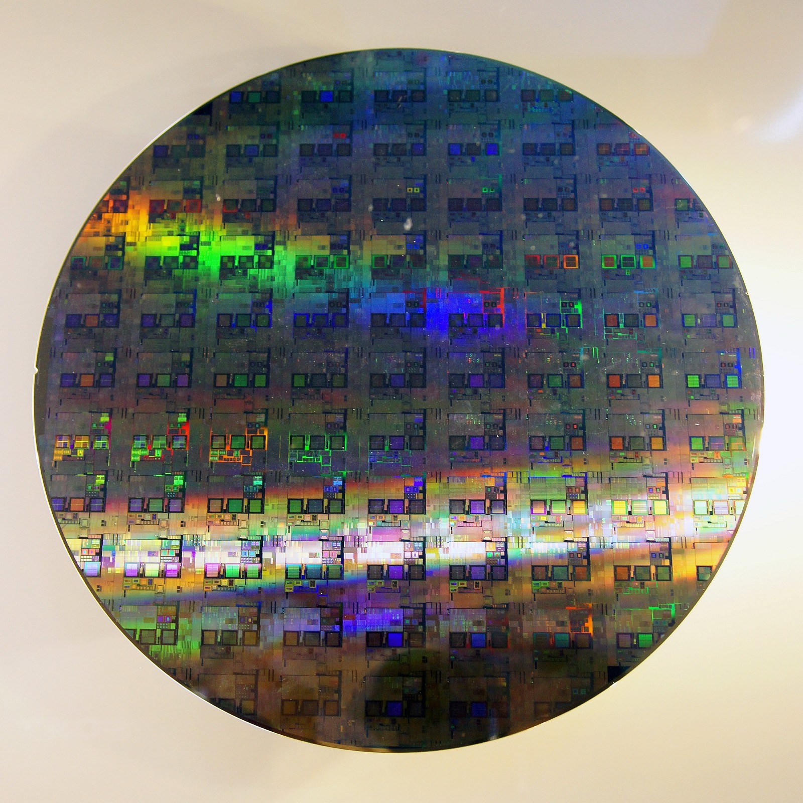 A bare 300mm silicon wafer with its characteristic mirror finish. Each wafer is patterned with hundreds of identical chips before being cut apart and, for HBM, thinned to a fraction of a hair's width.